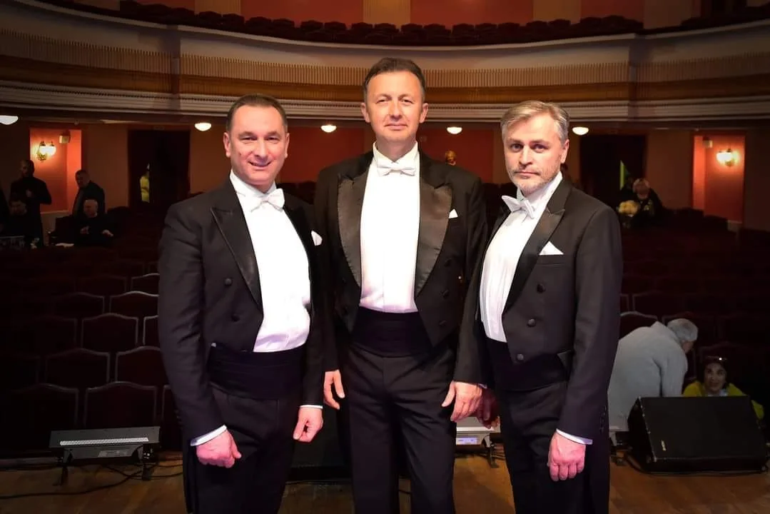 Три чоловіки у фраках на сцені театру