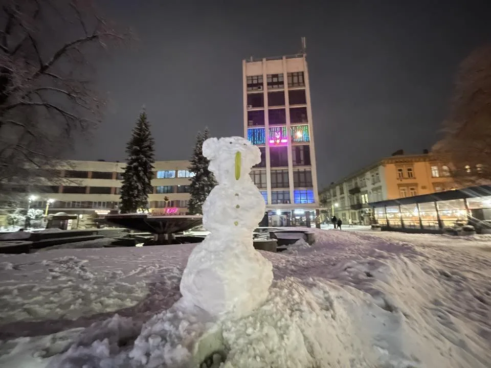 Сніговик перед міською будівлею вночі