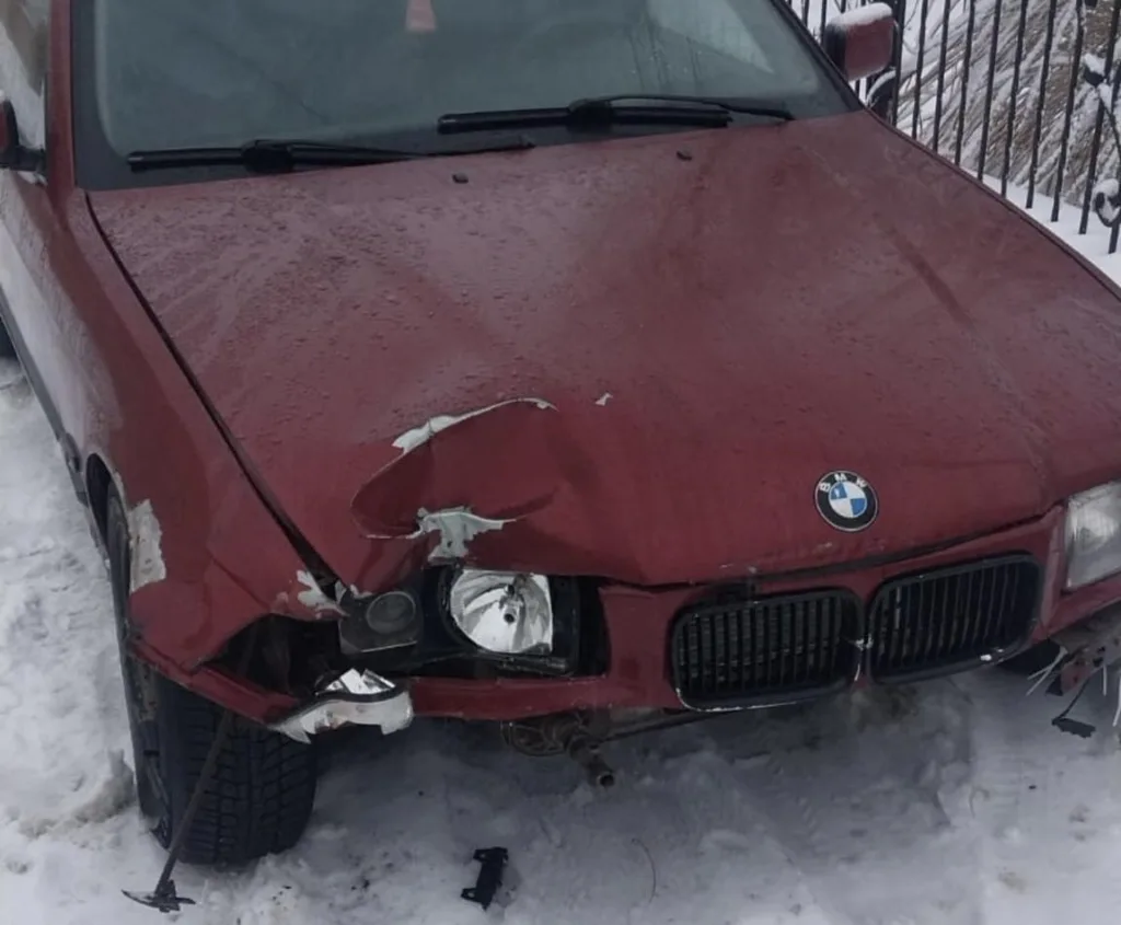 Пошкоджений червоний автомобіль на снігу