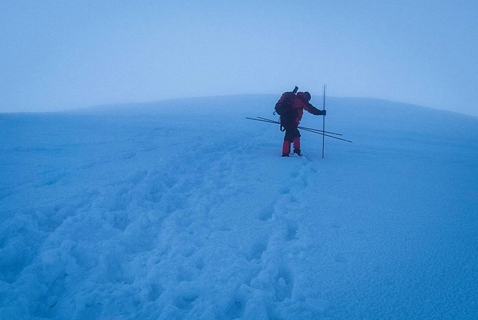 Альпініст йде сніговим схилом у тумані