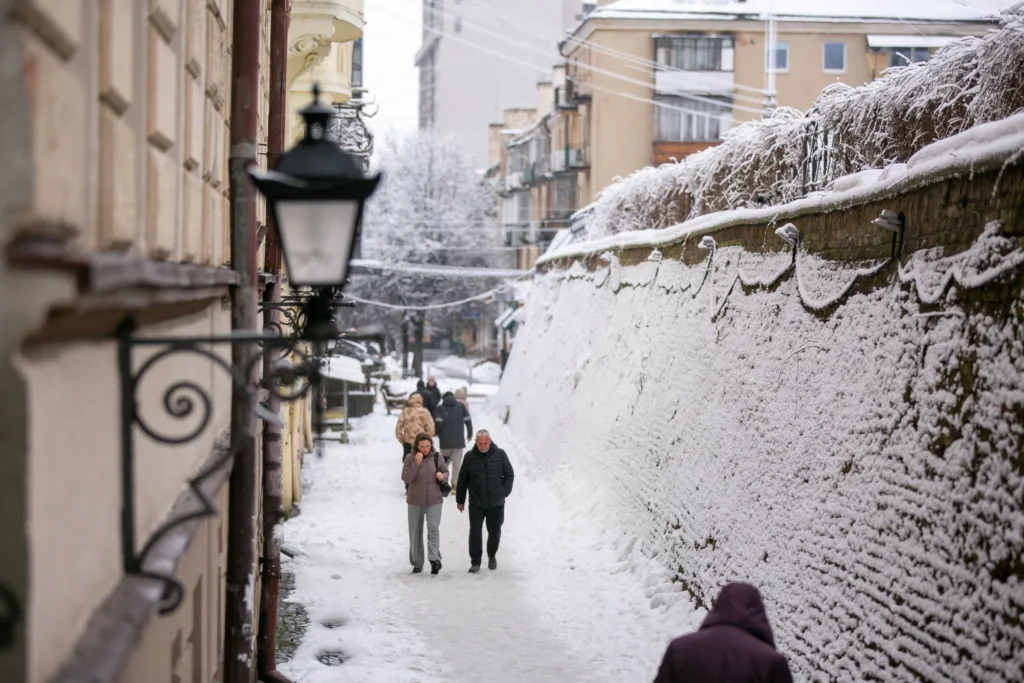 Люди йдуть засніженою вуличкою міста взимку