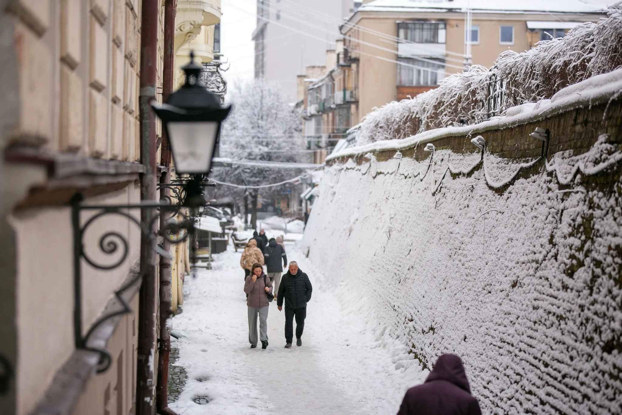Люди йдуть засніженою вуличкою міста взимку