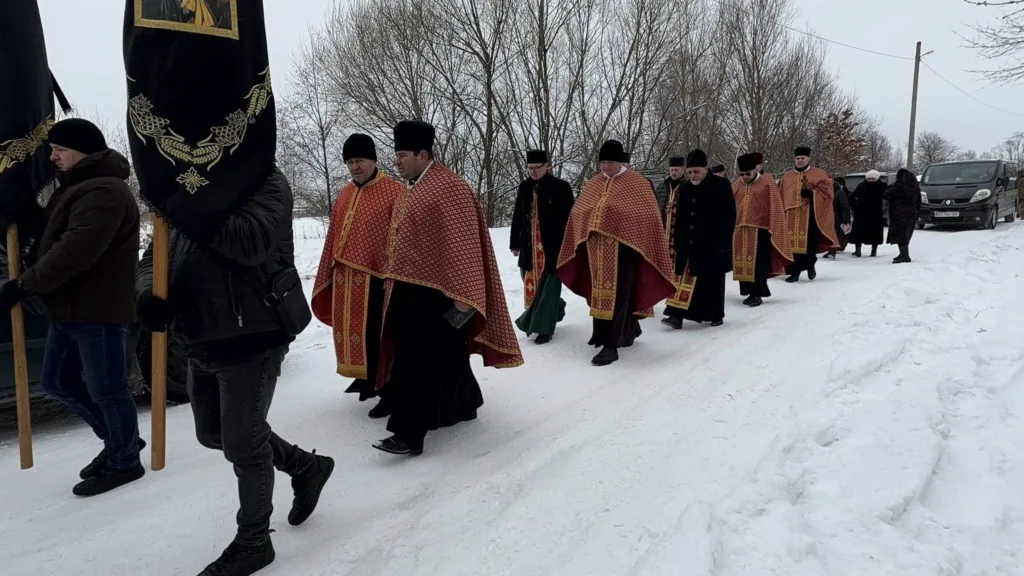Священики йдуть сніжною дорогою під час процесії