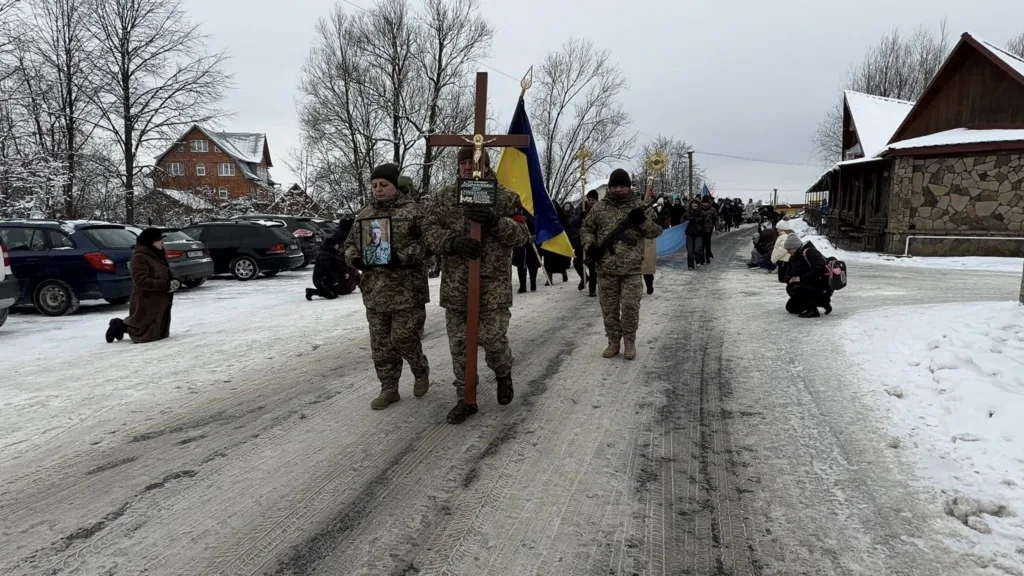 Військовий похорон, люди стоять на колінах на снігу
