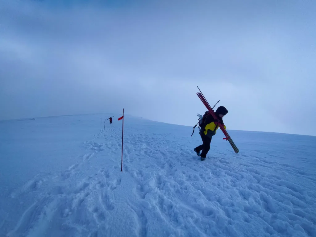 Альпініст несе лижі на сніговій горі