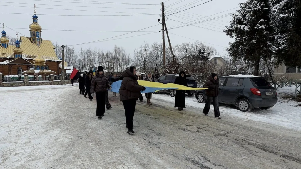 Люди несуть великий український прапор біля церкви
