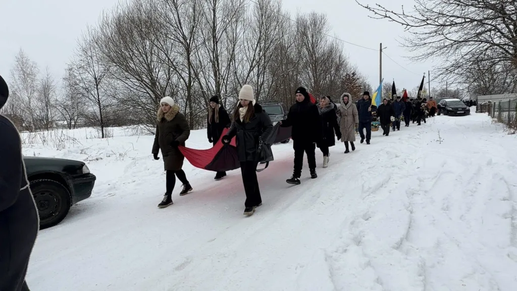 Люди йдуть зимовою дорогою під час похоронної процесії