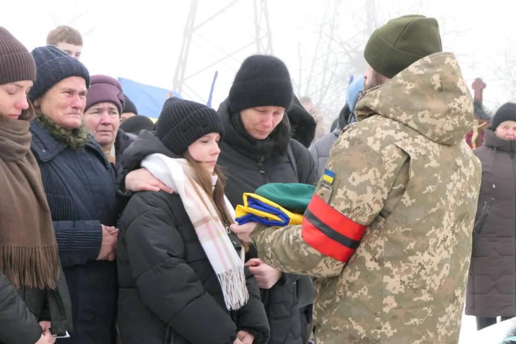 Військовий передає український прапор родині загиблого