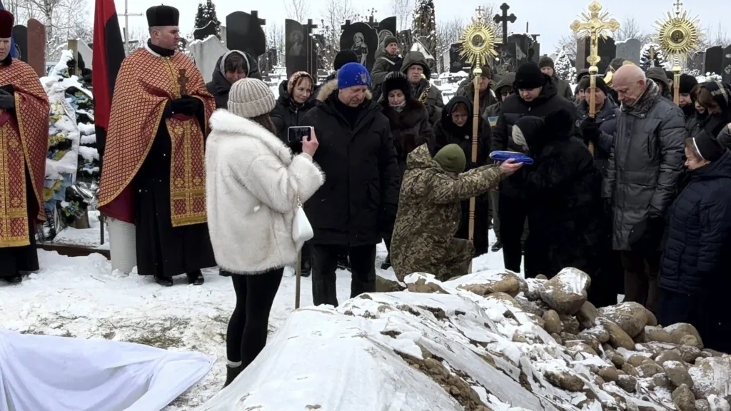 Похоронна церемонія на засніженому кладовищі