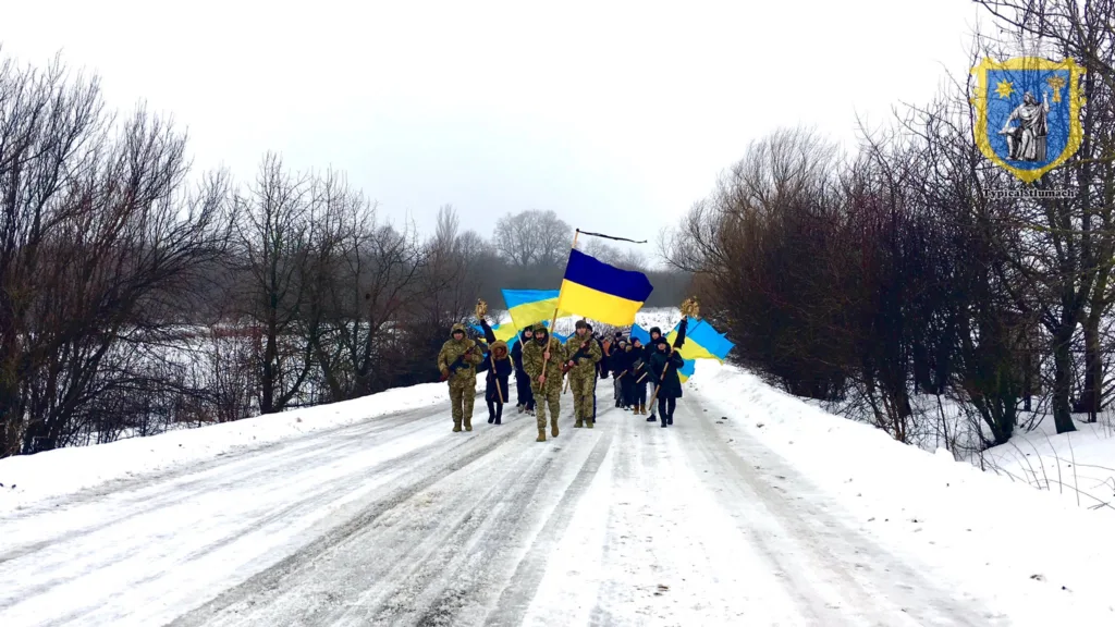 Марш з українськими прапорами взимку на сніговій дорозі