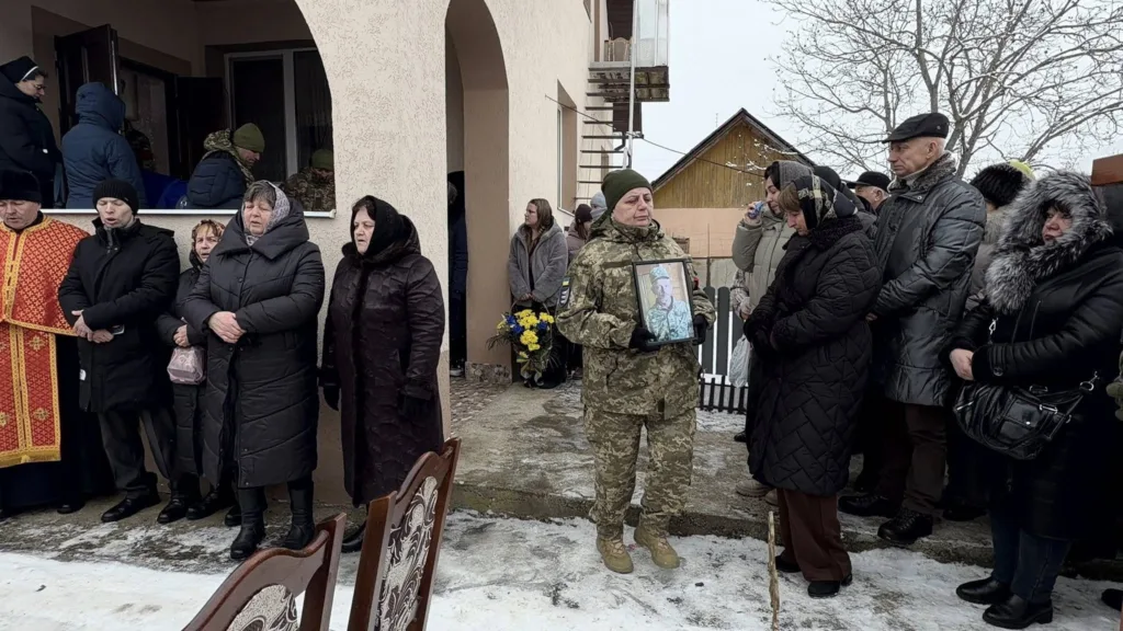 Люди прощаються із військовим біля будинку взимку