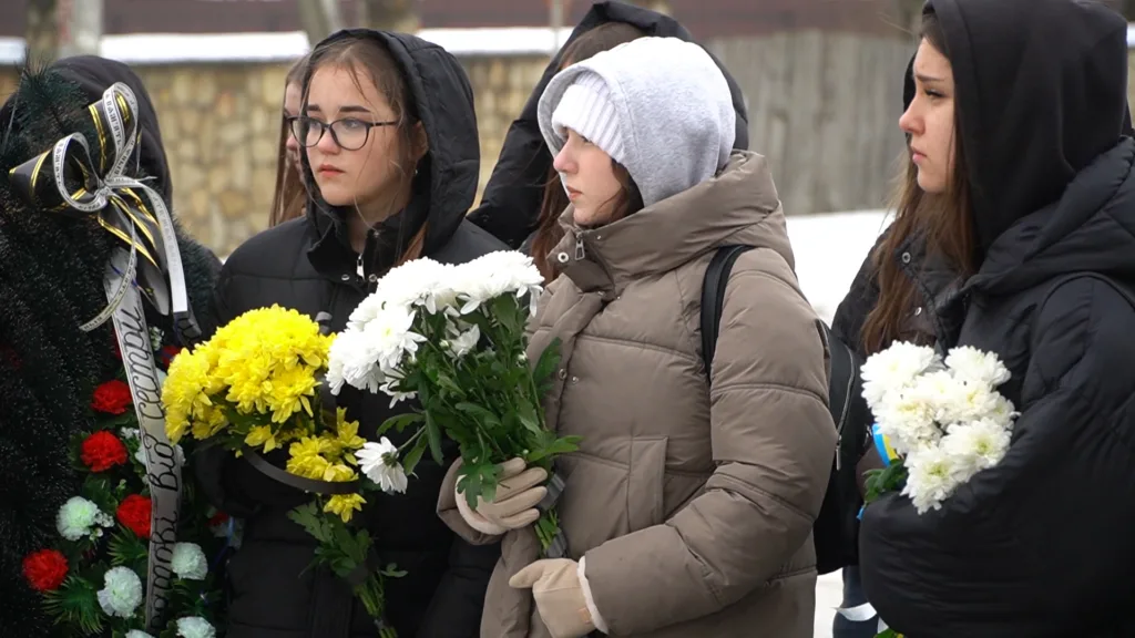 Люди з квітами на зимовому похороні