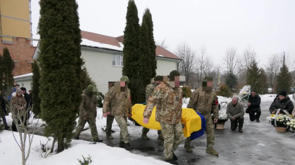 Військові несуть труну, накриту прапором України