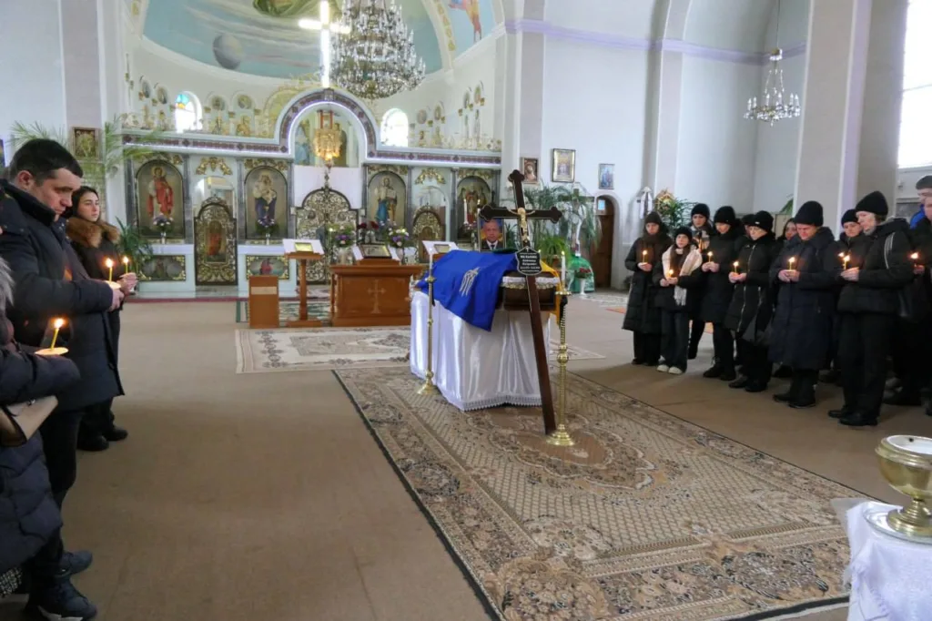 Поминальна служба в церкві, люди тримають свічки