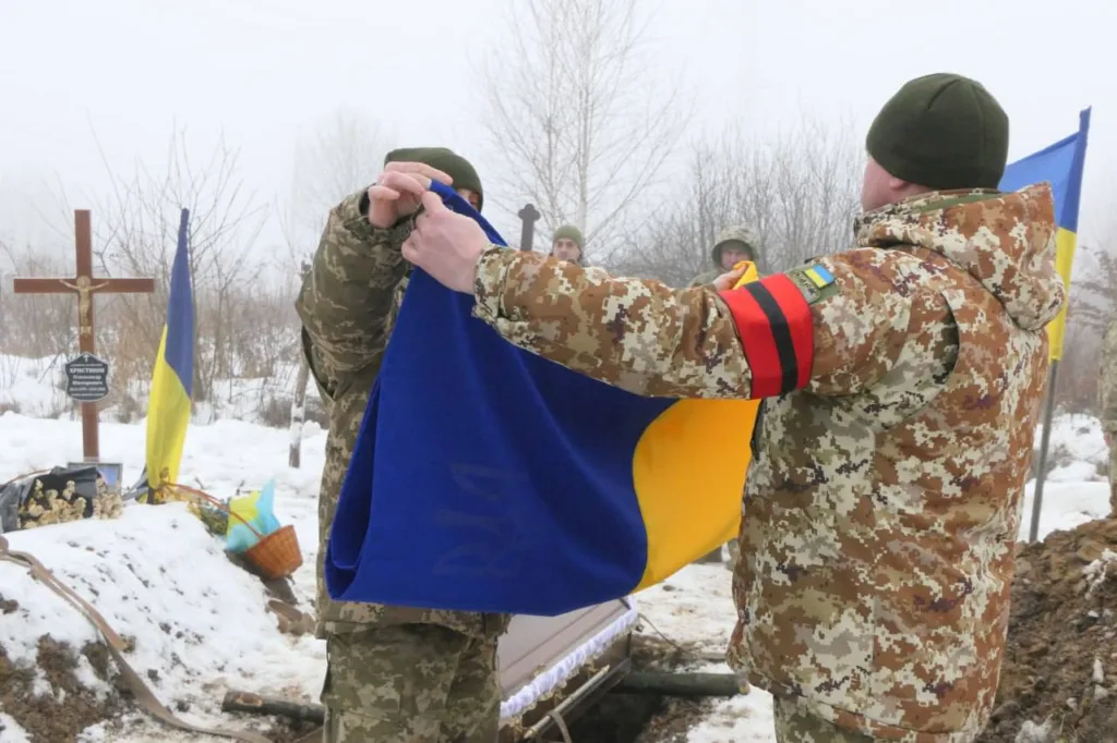 Військові складають український прапор на похороні