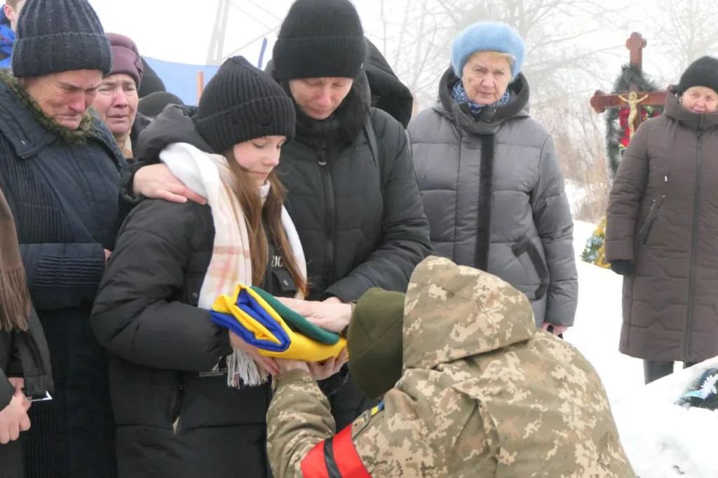 Прощання з військовим, люди тримають український прапор