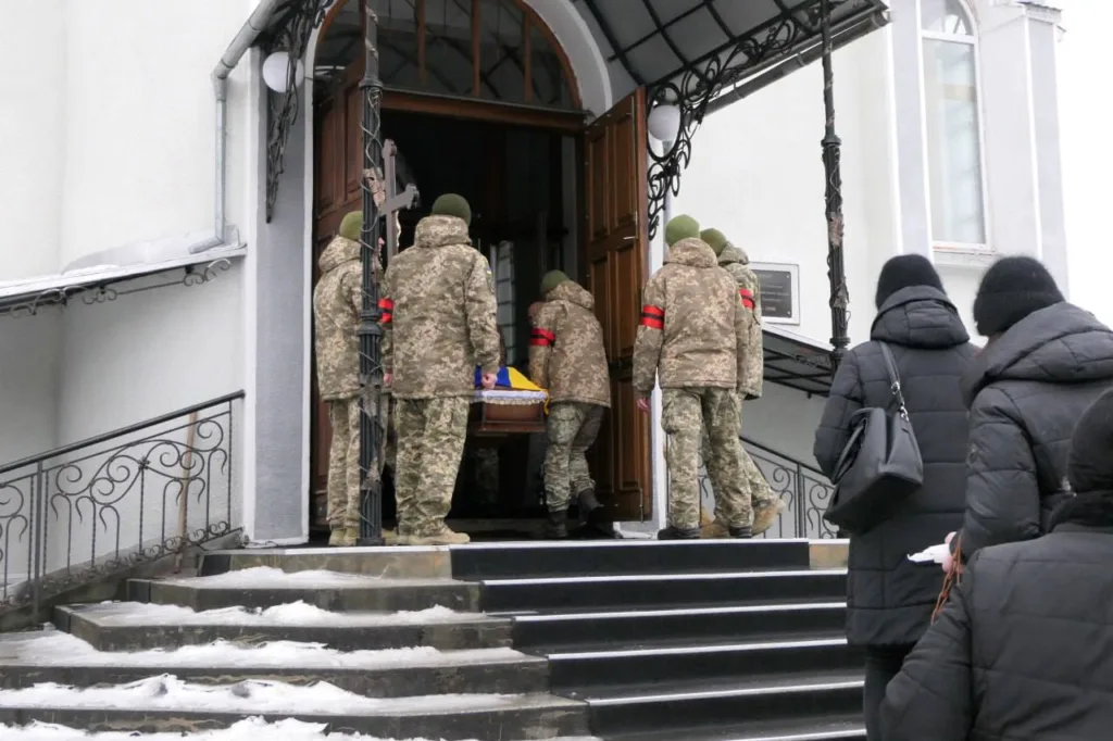 Військові несуть труну до церкви взимку