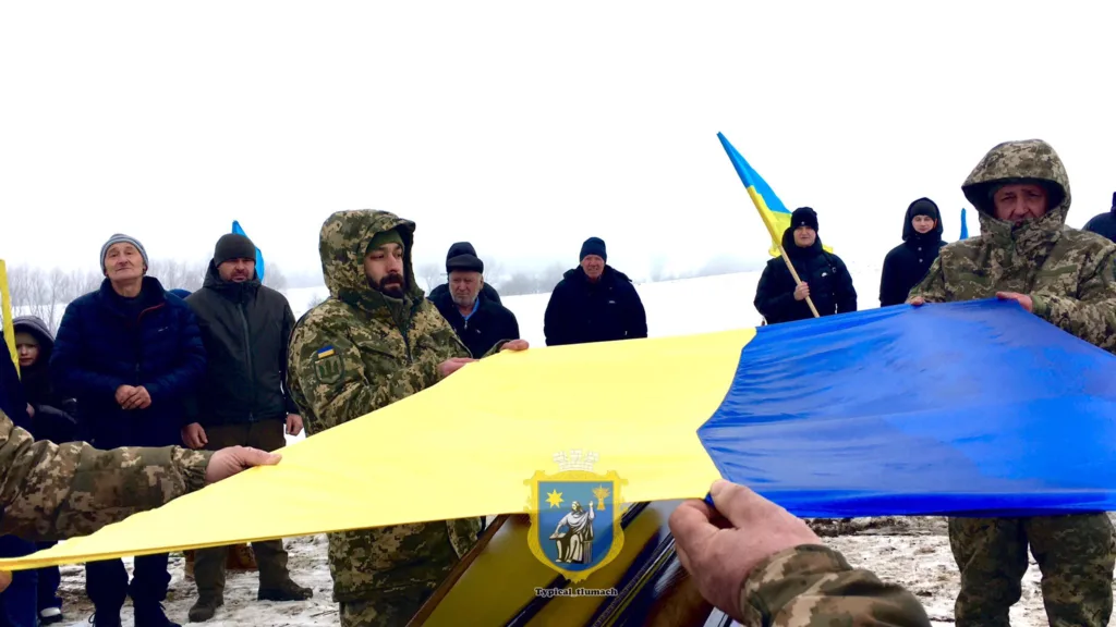 Військові тримають великий прапор України на морозі