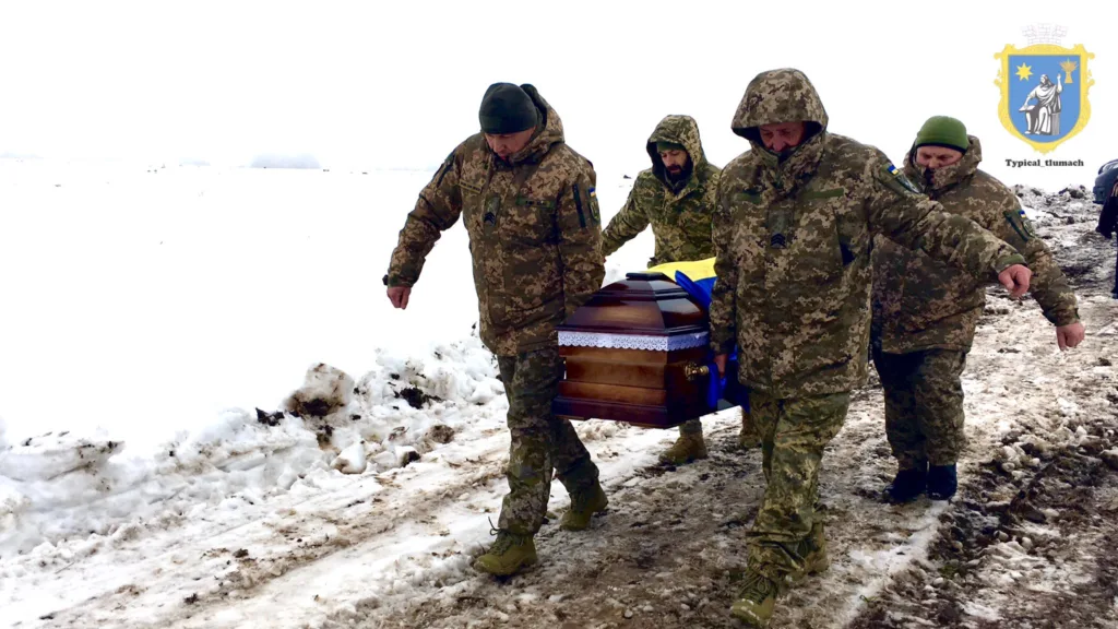Військові несуть труну українського солдата взимку