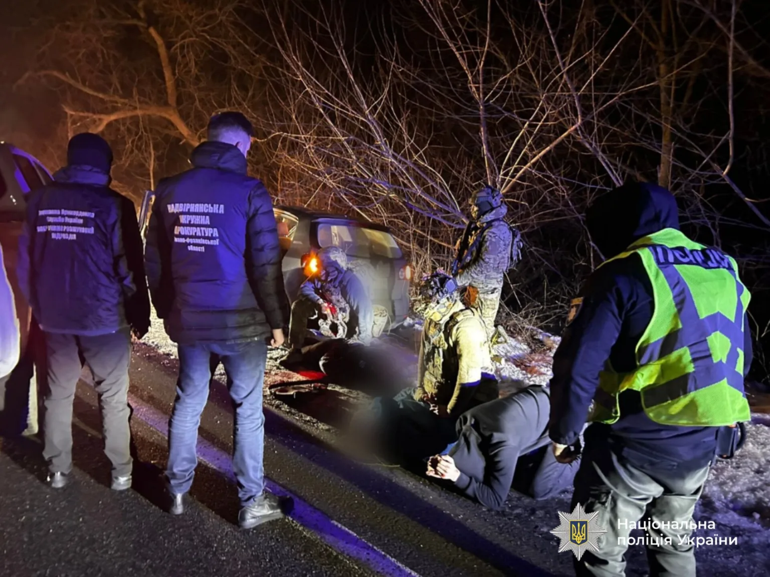 Поліція України затримує підозрюваних біля автомобіля вночі