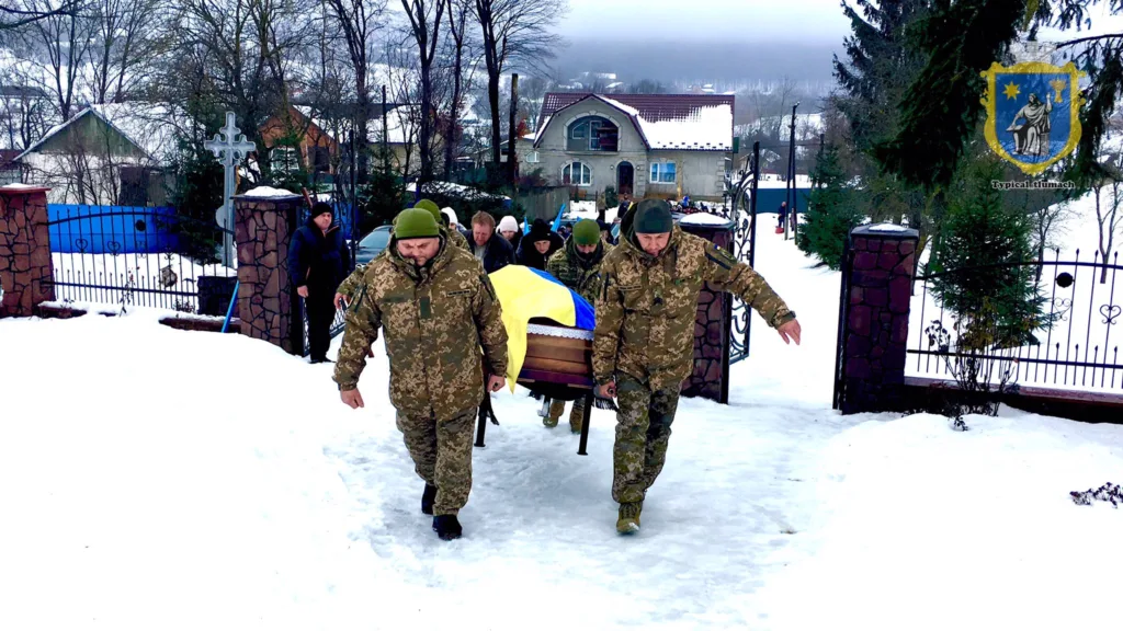 Військові несуть труну з прапором України взимку