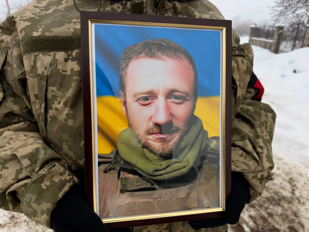 Військовий тримає фото перед прапором України