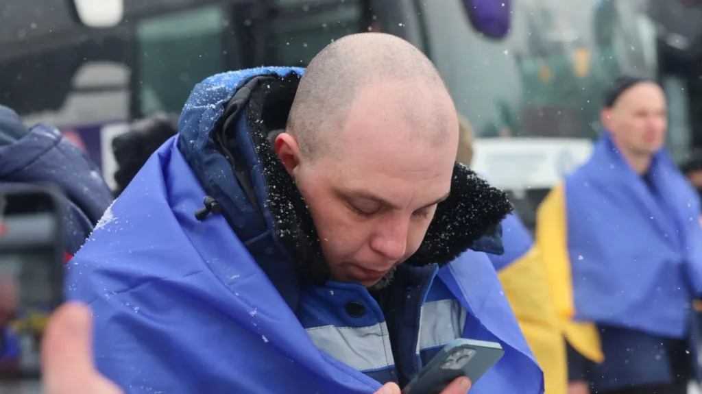 Чоловік у синій куртці дивиться на телефон