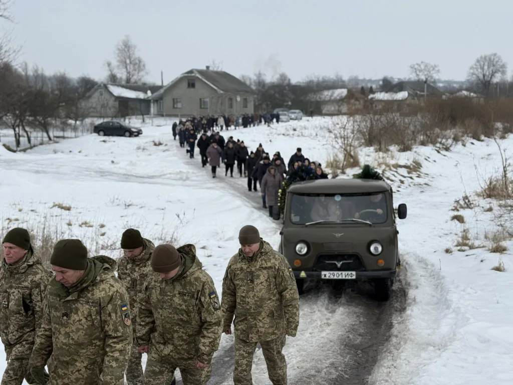 Військові та люди йдуть зимовою дорогою селом