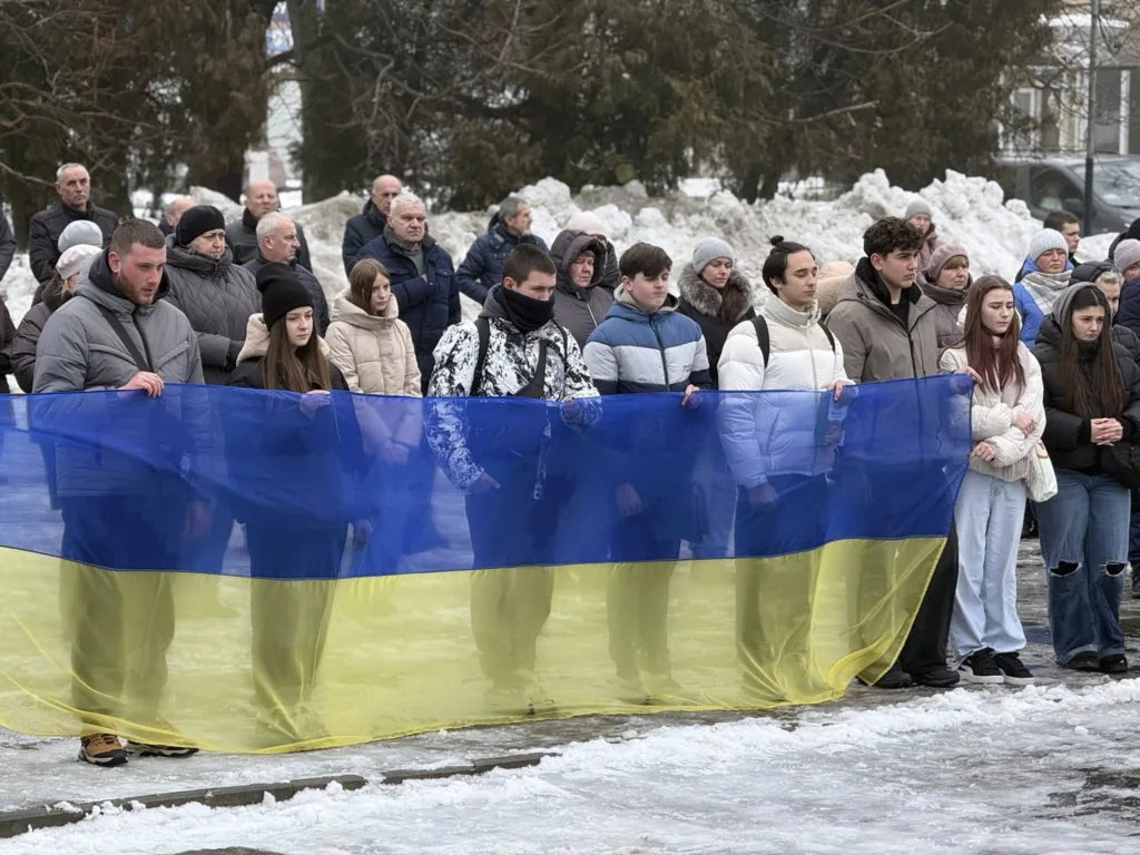 Люди тримають великий прапор України на вулиці