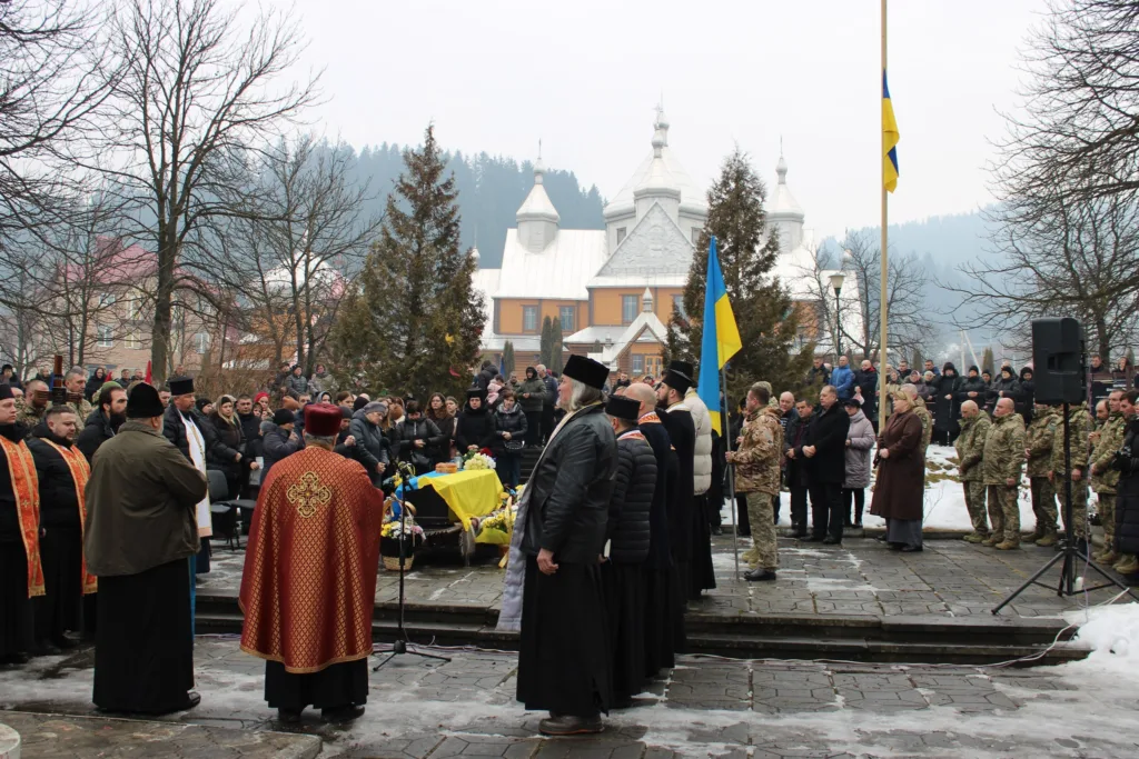 Поминальна церемонія біля церкви з українським прапором