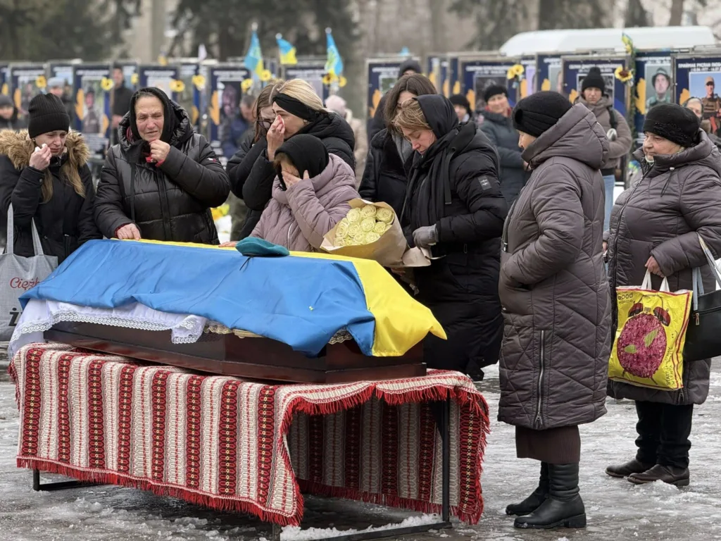 Люди прощаються з полеглим героєм під прапором України