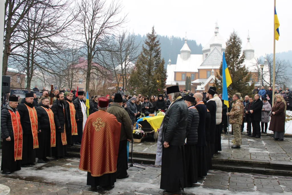 Поминальна церемонія під прапором України біля церкви