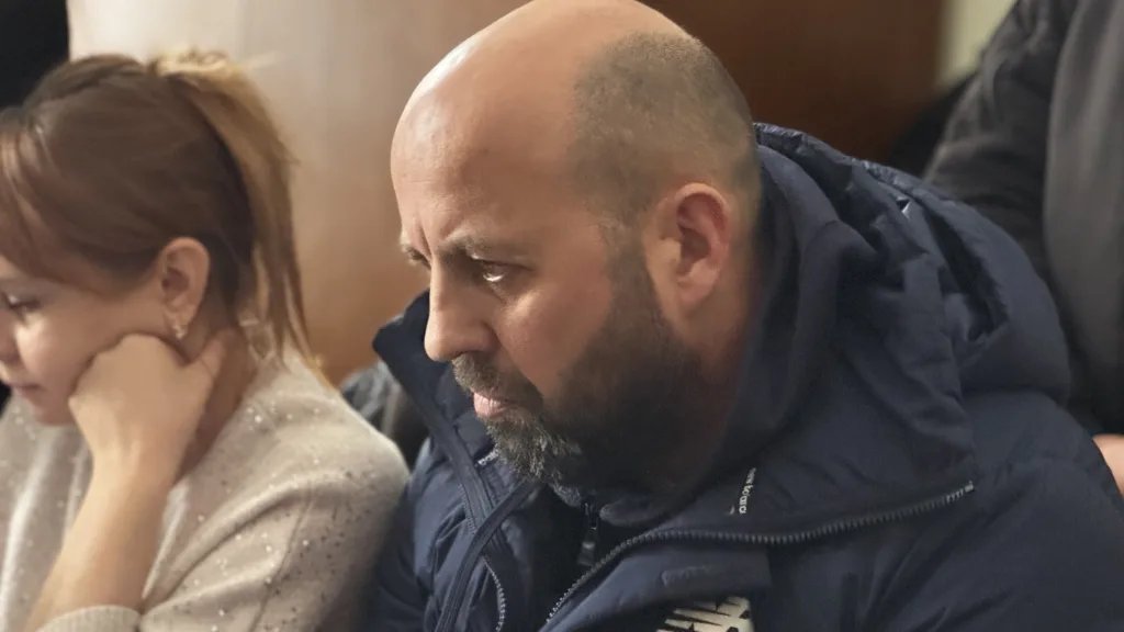 Двоє людей сидять поруч у приміщенні