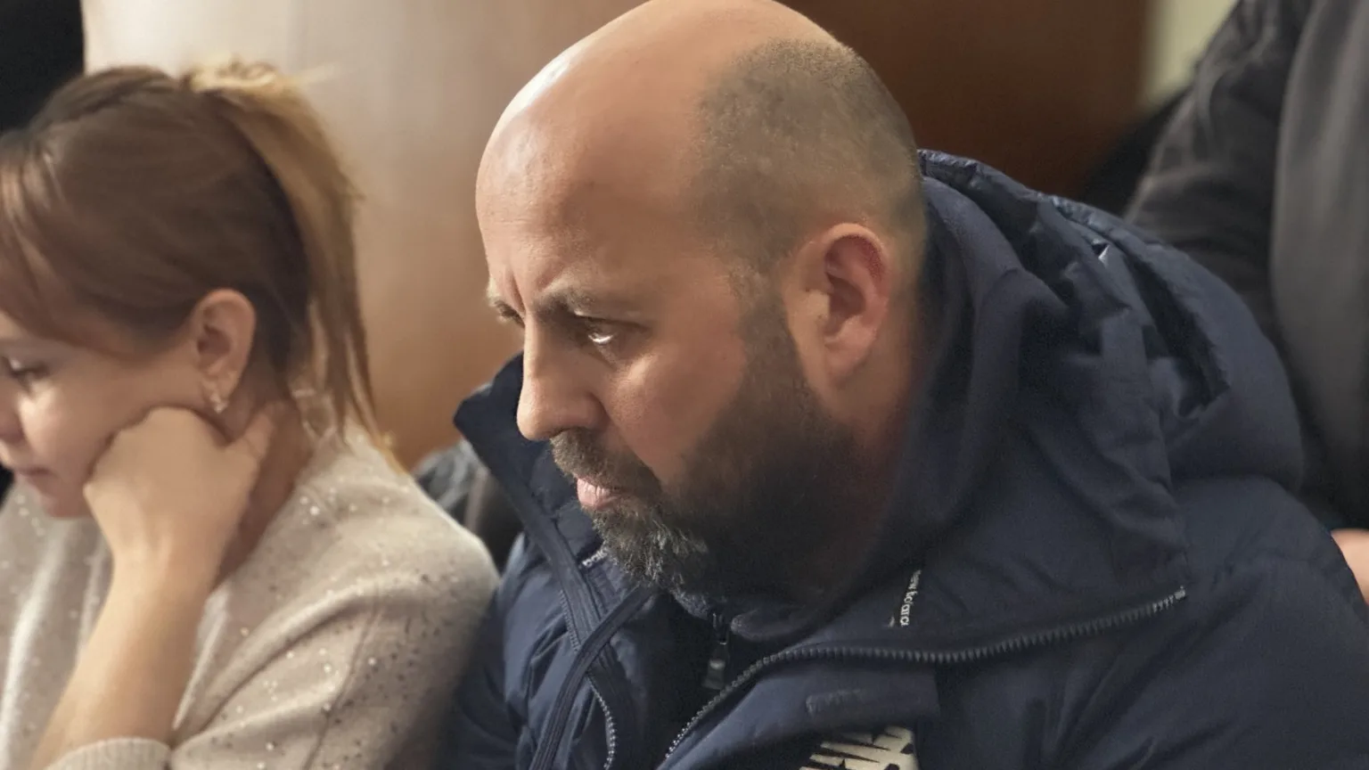 Двоє людей сидять поруч у приміщенні