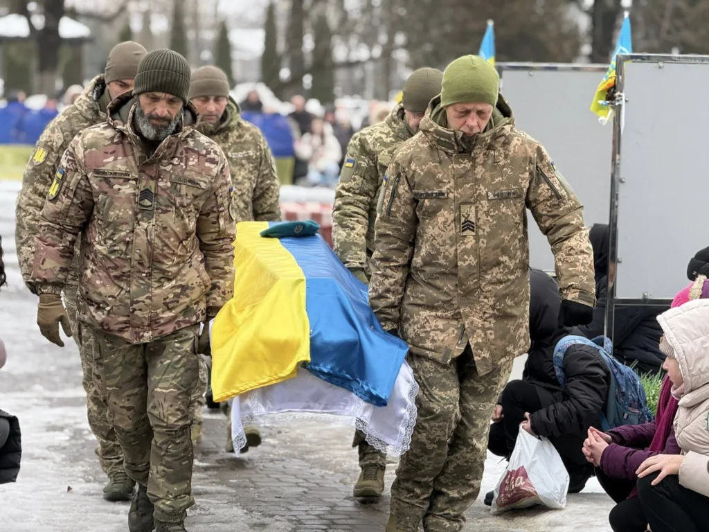 Військові несуть труну, накриту прапором України