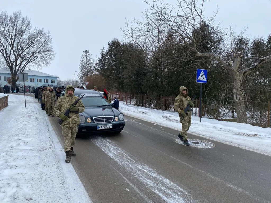 Військові йдуть зимовою дорогою поруч із автомобілем