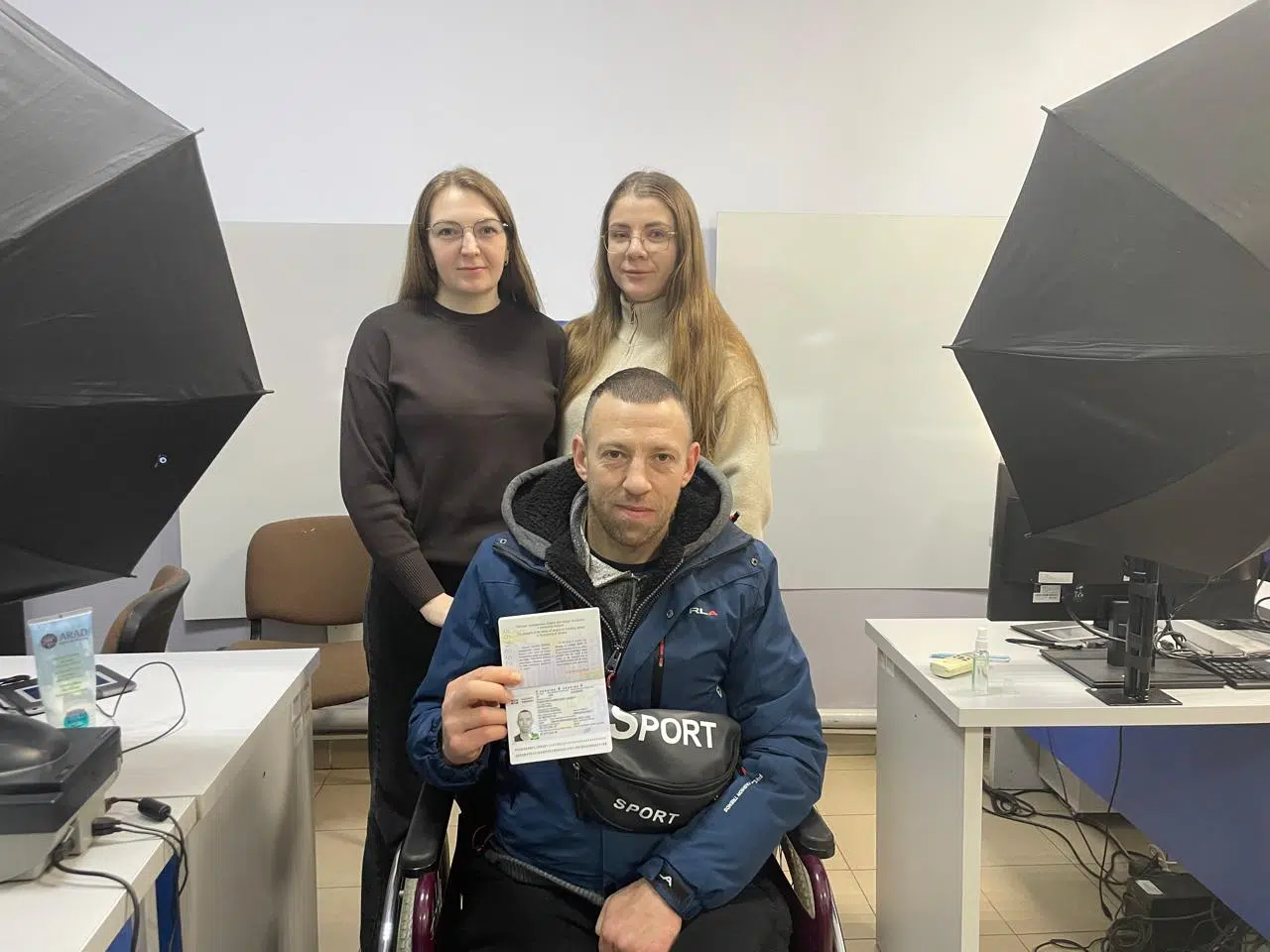 Чоловік у візку отримує паспорт у офісі