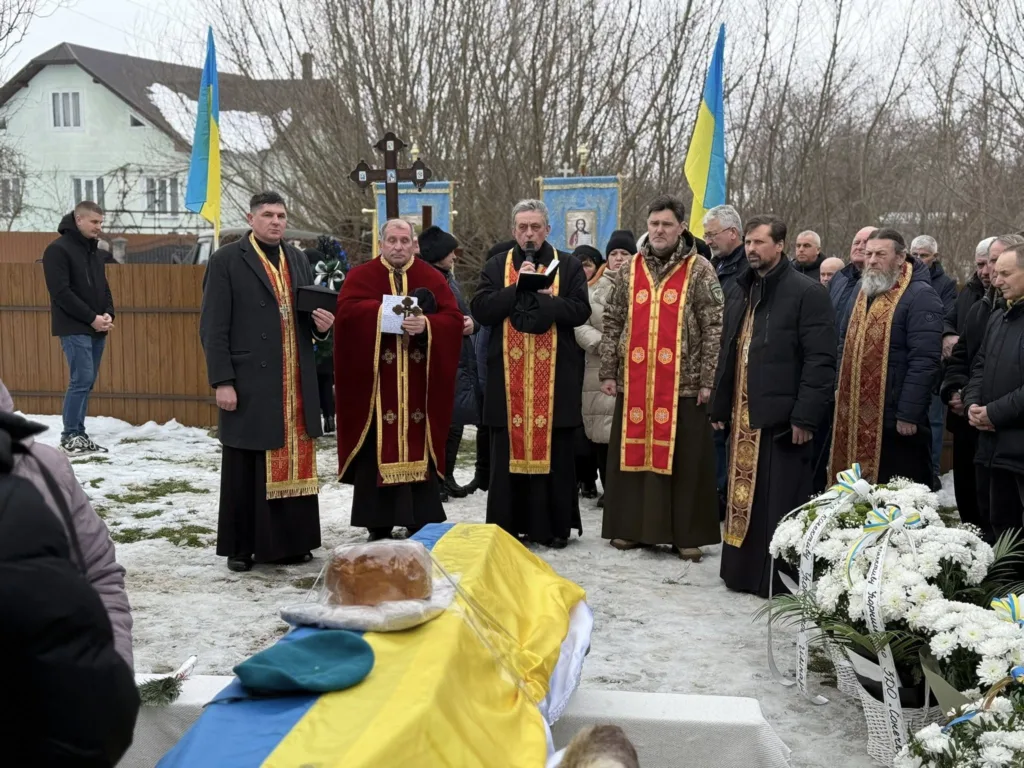 Священники проводять похоронну церемонію з українським прапором