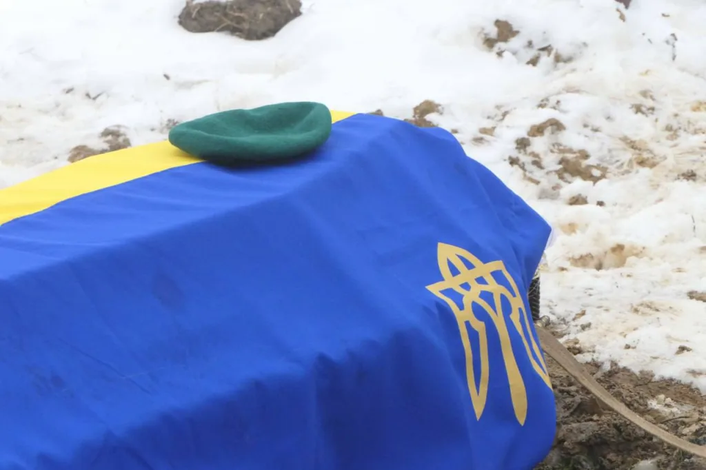 Урна, вкрита українським прапором, на снігу