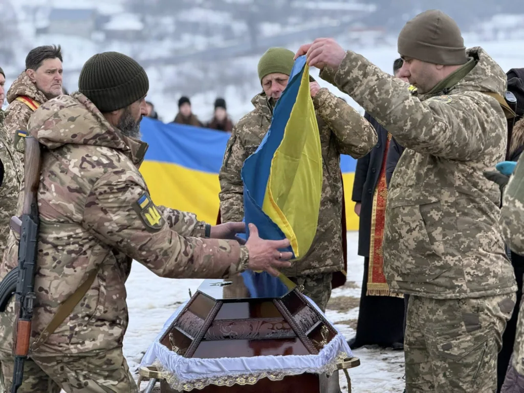 Військові накривають труну українським прапором