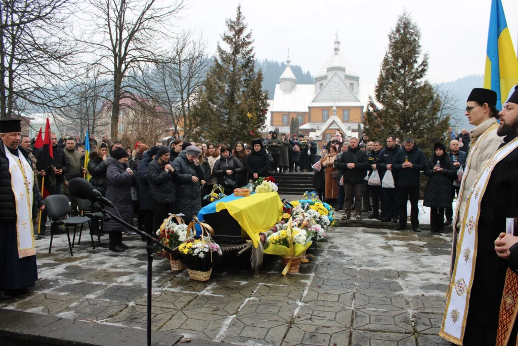Похоронна церемонія з українським прапором і священиками