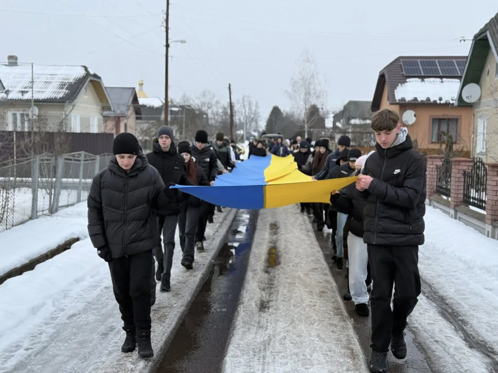 Люди несуть великий прапор України взимку