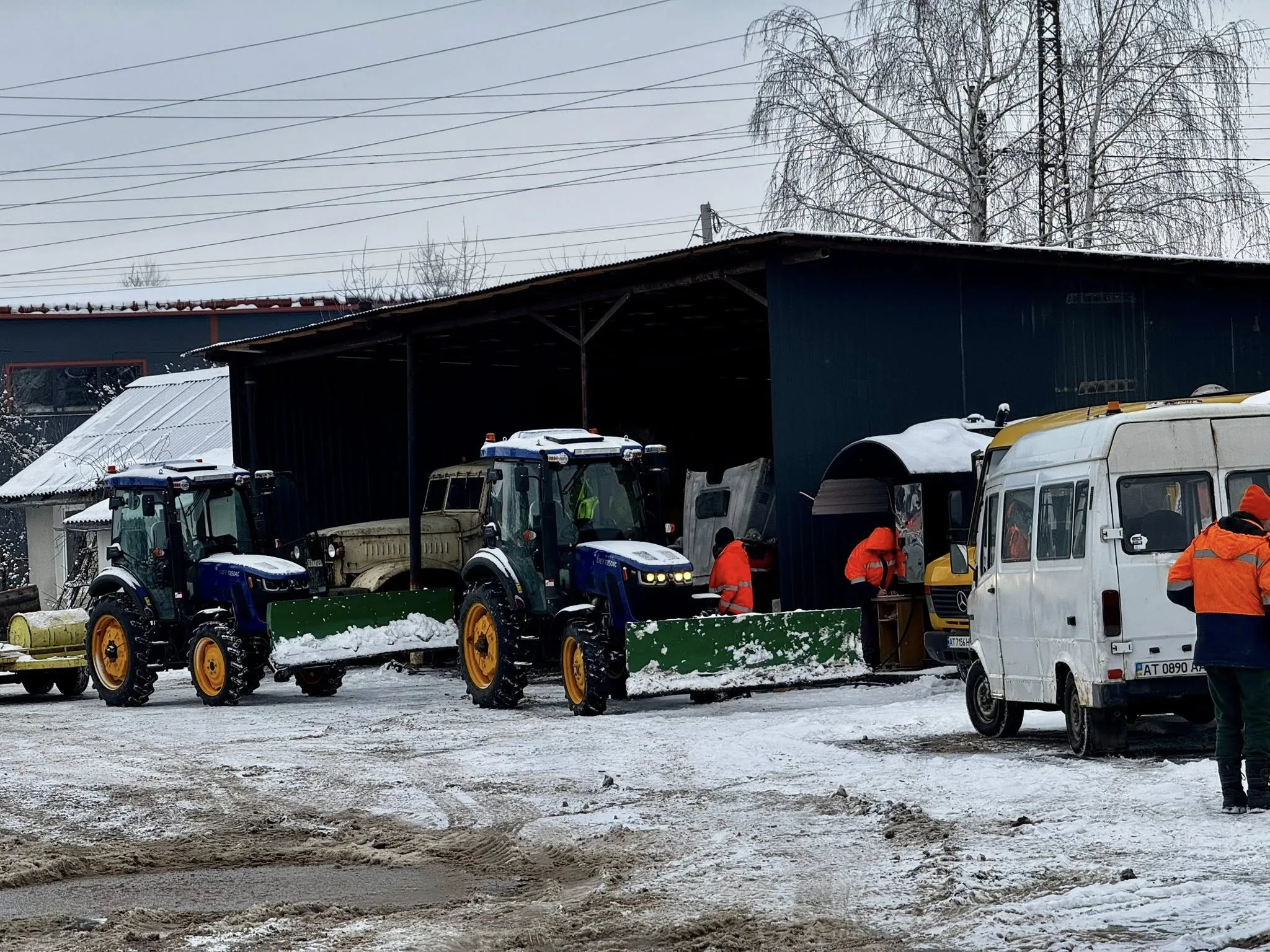 Трактори прибирають сніг біля гаража взимку