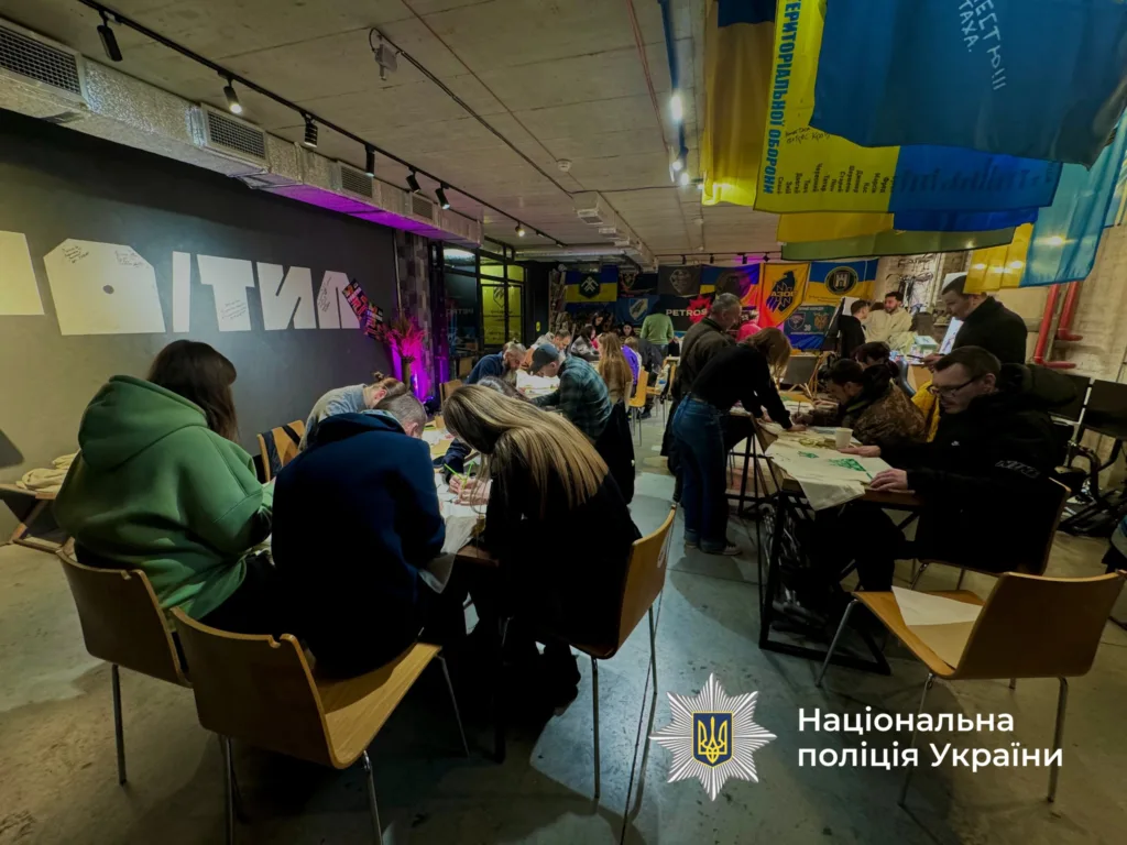 Люди малюють у приміщенні з українськими прапорами