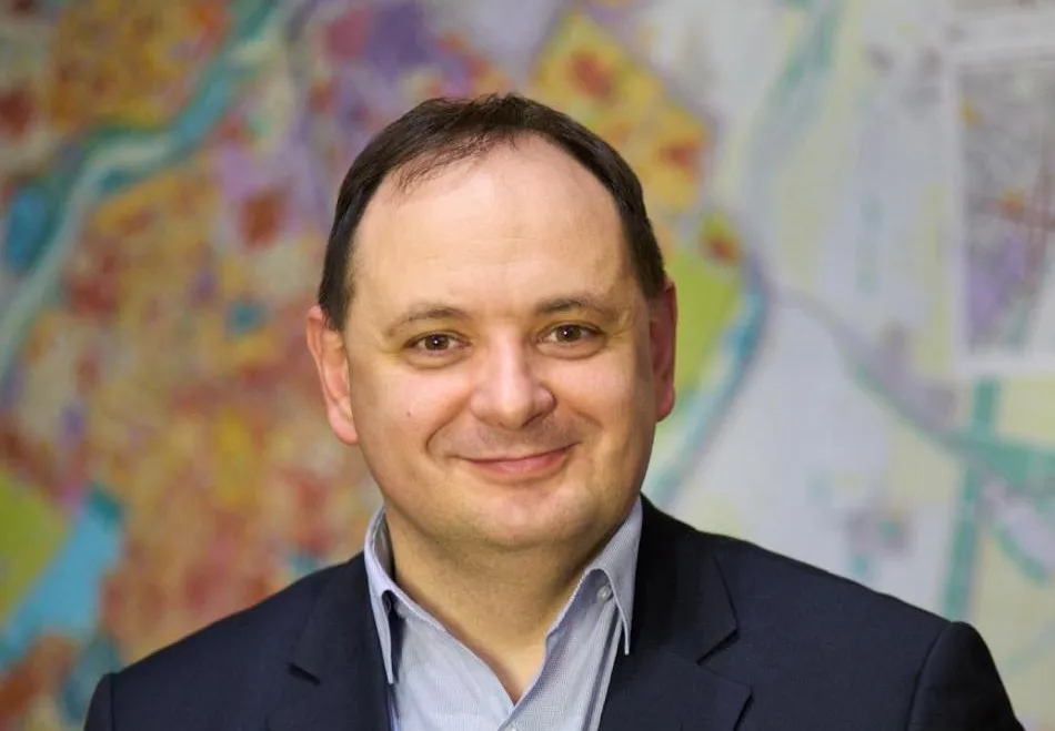 Чоловік у костюмі перед кольоровою картою