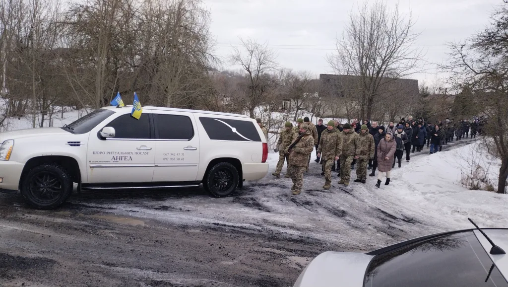 Військовий похоронний кортеж у зимовому селі