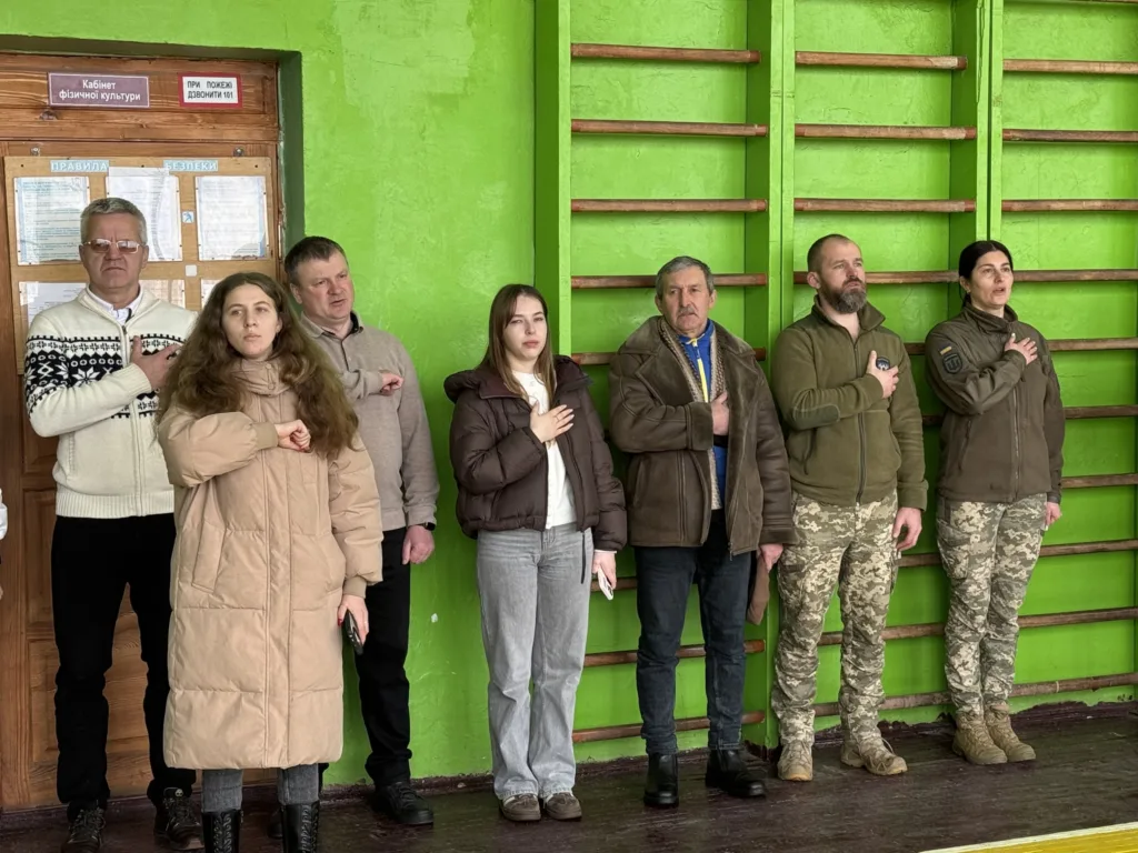 Люди стоять у спортзалі з руками на серці