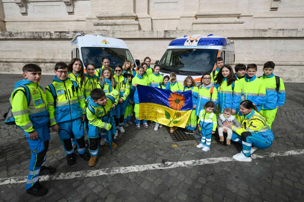 Діти у формі тримають український прапор біля швидких