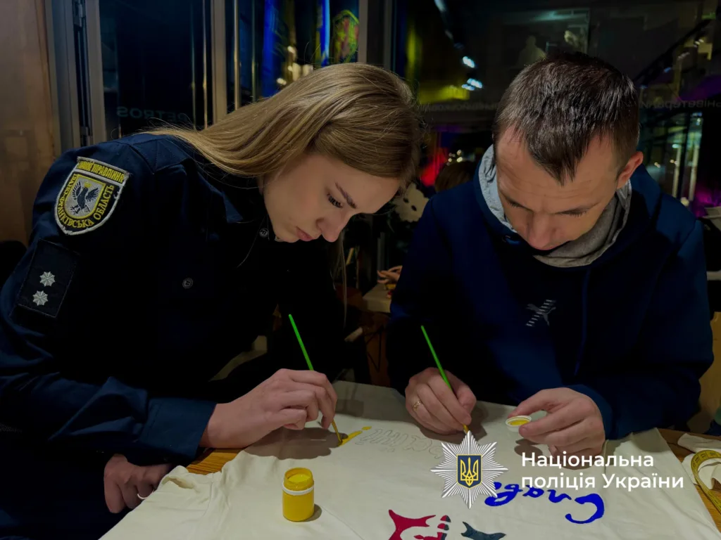 Поліцейська та чоловік разом малюють фарбами