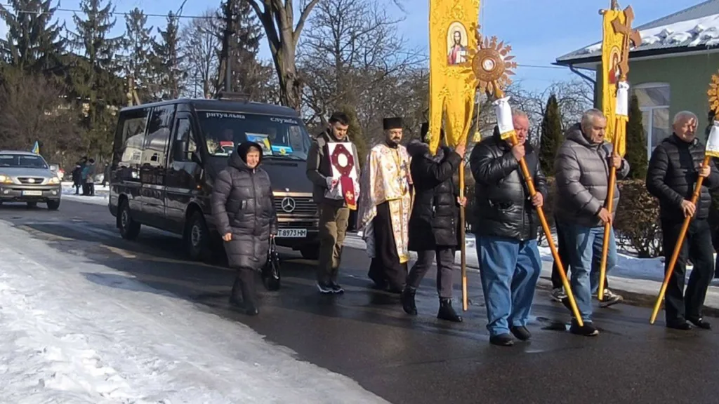 Релігійна хода з прапорами та священником взимку